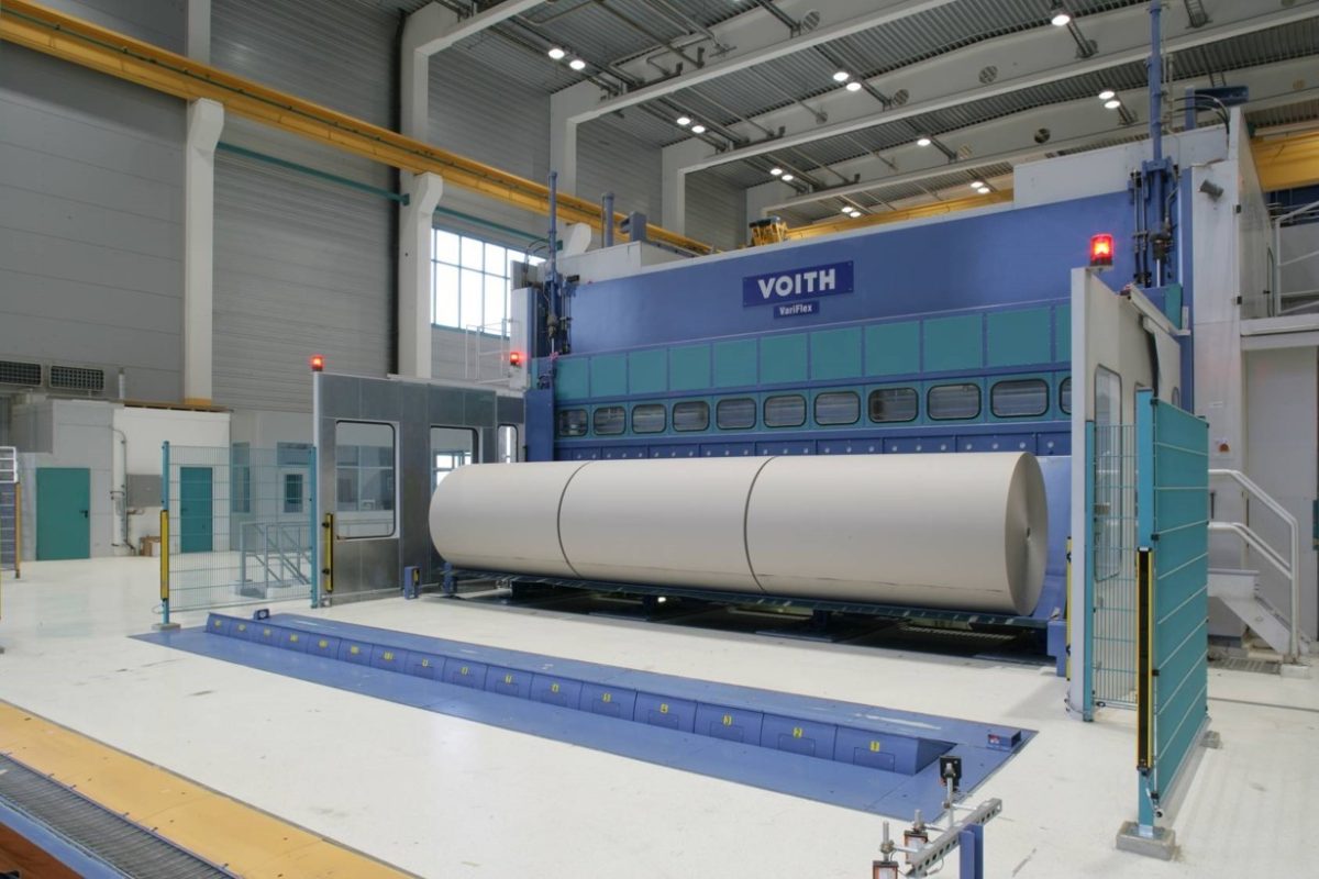 Große Papierrolle vor blauer Wickelmaschine in Produktionshalle