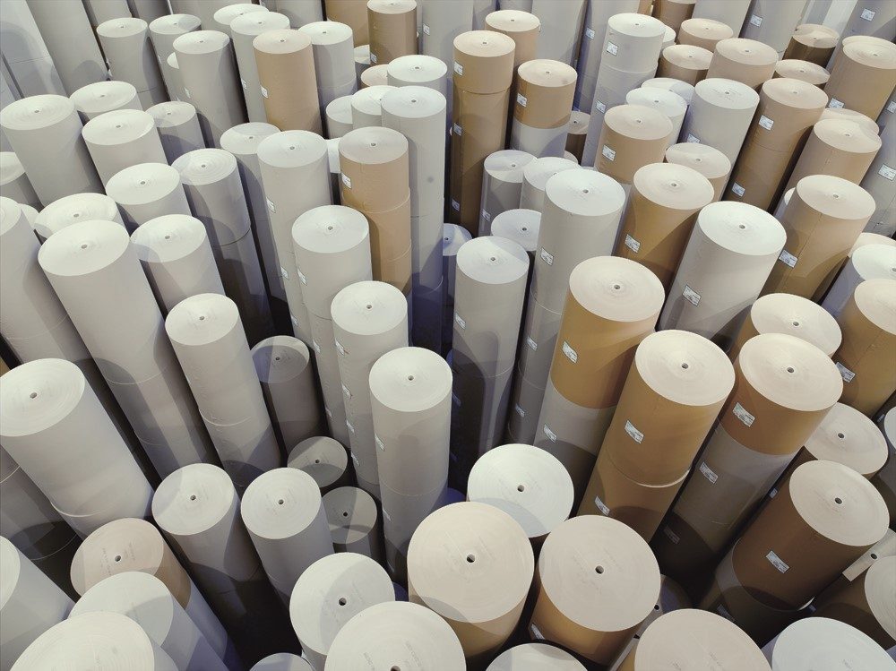 Große Papierrollen aus recyceltem Altpapier stehen dicht an dicht im Lager.
