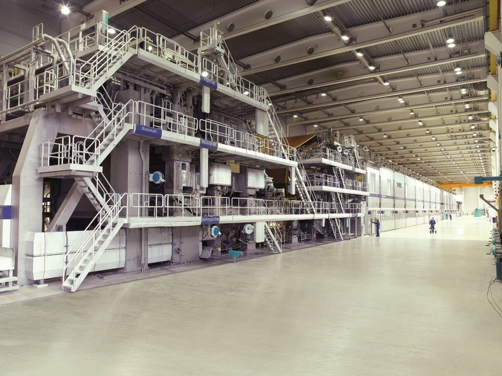 Große Papiermaschine mit Plattformen und Treppen in einer Industriehalle
