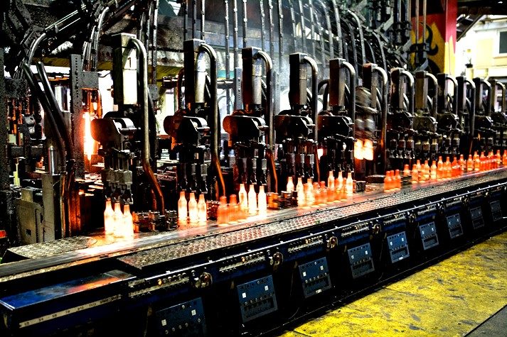 Glühend heiße Glasflaschen werden in Formmaschinen einer Glashütte produziert.